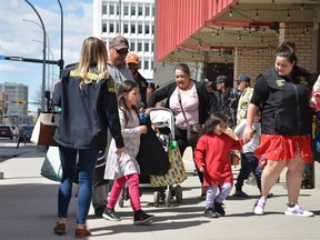 Residents from the La Loche region in northern Saskatchewan get off a bus and head into a hotel in Regina on Friday, May 5, 2023, after they were evacuated following ongoing wildfires in the region.