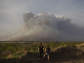 Residents of Prince Albert, Sask., watch a plume of smoke rise from a forest fire burning northeast of the city on May 17, 2021.