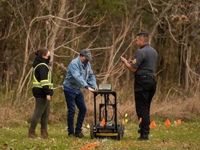 Community members, joined by Six Nations Police, conduct a search for unmarked graves using ground-penetrating radar on the 500 acres of the lands associated with the former Indian Residential School, the Mohawk Institute, in Brantford, Ont., Tuesday, Nov. 9, 2021. Indigenous communities searching for unmarked graves have seen a rise in individuals denying the disappearances and deaths of Indigenous children in the residential school system, according to a new report from the federal government's special interlocutor on unmarked graves.