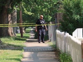 a police officer stands on a sidewalk with yellow tape visible