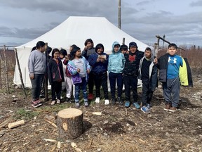 The third grade class at the Sheshatshiu Innu School in Labrador stands outside a traditional Innu tent on Wednesday, May 10, 2023, set up behind their school. Inside, they got to watch three elders make Innu doughnuts.