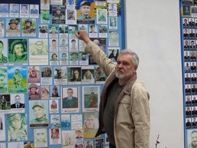 Yuri Pisarenko, whose grandson was killed in the war, stands in front of the memory wall in Kyiv on Tuesday, June 13, 2023. Pisarenko was there to replace a faded photograph of his grandson.