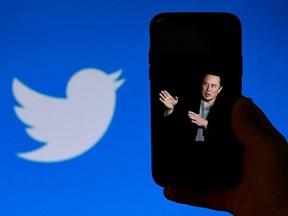 In this photo illustration, a phone screen displays a photo of Elon Musk with the Twitter logo shown in the background, on October 4, 2022, in Washington, DC.