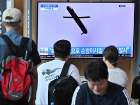 People watch a television screen showing a news broadcast with file footage of a North Korean missile test, at a railway station in Seoul on July 22, 2023.