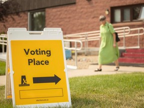 Voters walk past a sign signifying where to vote for the Provincial byelection outside the New Hope Lutheran Church on Friday, Aug. 4, 2023.