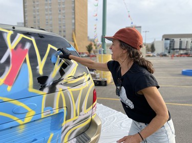 Carrie Catherine laughs while spraypainting a car as part of a public art project