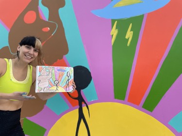 Dakota Ray Hebert shows off a sketch of their mural-in-progress at the Urban Canvas Street Party on September 8, 2023.