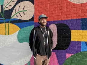L'artiste Josh Jacobson se tient devant sa nouvelle fresque murale au Confederation Mall à Saskatoon, en Saskatchewan, le 14 septembre 2023.