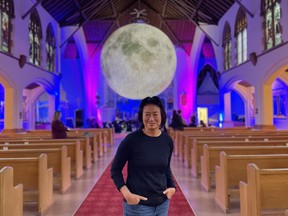 Saskatoon Symphony Orchestra guest conductor Judith Yan stands in front of the orchestra, and a giant hanging moon, in St. John’s Cathedral in Saskatoon, Saskatchewan on September 14, 2023.