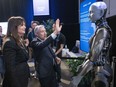 Federal Industry Minister Francois-Philippe Champagne says hello to an AI robot as Helene Desmarais, executive chairwoman, of IVADO Labs looks on at the All In artificial intelligence conference Wednesday, September 27, 2023 in Montreal.