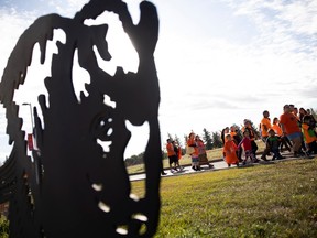 Marchers walk past First Nations University of Canada during a community smudge walk to honour residential school survivors and victims. Photo taken on Thursday, September 28, 2023 in Regina.