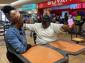 Restaurant owner Shalom Ogoh, left, and marketing consultant Fumnanya Mordi embrace in celebration of the one-year anniversary of the Nigerian shop in Prince Albert.