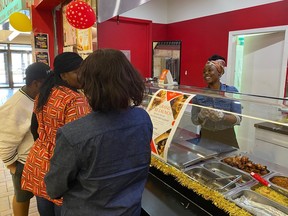 Restaurant owner Shalom Ogoh, right, provides service to clients at Nigerian shop Suyah To-Go in Prince Albert on Sept. 10, 2023.