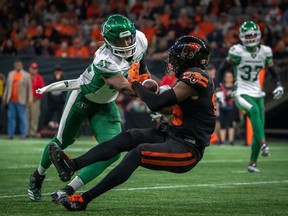 Saskatchewan Roughriders linebacker Derrick Moncrief (42) tackles BC Lions wide receiver Dominique Rhymes (19) as he completes a pass during second half of CFL football action in Vancouver, B.C., Friday, Sept. 29, 2023.