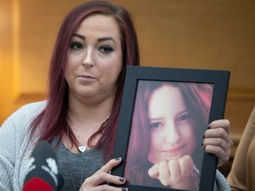 Sarah Mackenzie holds up a picture of her 14-year-old child "Bee" who took her life this spring amid the pressures of transitioning.