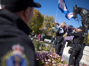 Miki Mappin holds a transgender flag as she is carried off a statue of the queen by members of the Regina Police Service during opposing rallies regarding the pronoun policy in school, a policy which was the subject of a court case and injunction mere weeks ago. Attendees gathered outside the Saskatchewan Legislative Building on Tuesday, October 10, 2023 in Regina. KAYLE NEIS / Regina Leader-Post