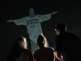 Fans look up at the Christ the Redeemer statue that is illuminated with a welcome message to American singer Taylor Swift, in Rio de Janeiro, Brazil, Thursday, Nov. 16, 2023.