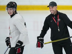 Canada's head coach Alan Letang, right, laughs with forward Fraser Minten at practice during Canadian World Juniors selection camp in Oakville, Ont., on Monday, December 11, 2023. THE CANADIAN PRESS/Nathan Denette