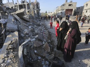 Palestinians look at the destruction by the Israeli bombardment of the Gaza Strip in Rafah, Monday, Dec. 4, 2023.