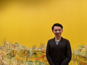 Tak Pham, curator of Human Capital, stands with the painting Re-grounding by artist Marigold Santos in the Human Capital exhibition at the University of Saskatchewan's College Art Gallery in Saskatoon, Saskatchewan on January 12, 2024.