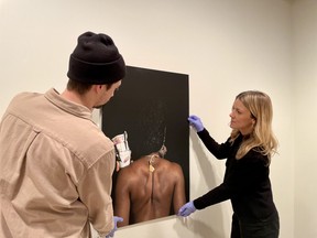 (L-R) University of Saskatchewan art galleries coordinating curator Cole Thompson and curator Leah Taylor install artwork for the Human Capital exhibition in the College Art Gallery in Saskatoon, Saskatchewan on January 12, 2024.