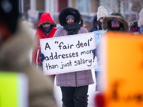 A person holds a sign while walking at a demonstration site during a provincewide, one-day strike organized by the members of Saskatchewan Teachers' Federation in Saskatoon, Sask., on Monday, Jan. 22, 2024. Saskatchewan teachers were expected to stop noon-hour supervision to get the government to address their demands.