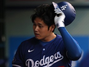 ANAHEIM, CALIFORNIA - MARCH 26: Shohei Ohtani #17 of the Los Angeles Dodgers removes his helmet in the dugout after striking out in the third inning during an exhibition game against the Los Angeles Angels at Angel Stadium of Anaheim on March 26, 2024 in Anaheim, California.
