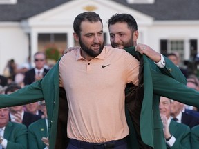 Jon Rahm, of Spain, puts the green jacket on winner Scottie Scheffler after the Masters golf tournament at Augusta National Golf Club Sunday, April 14, 2024, in Augusta, Ga.