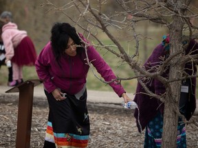 Colleen Whitedeer, whose brother has been missing since 2014, pours water on the Missing Persons Tree and Bench in Regina's Wascana Park during an event to proclaim Missing Persons Week in Saskatchewan on Tuesday, April 30, 2024.