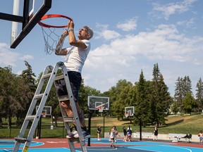 Community member Marcel D'Eon replaces a basketball net at the Pawatetan basketball courts. Photo taken in Saskatoon, Sask. on Tuesday, August 13, 2024.