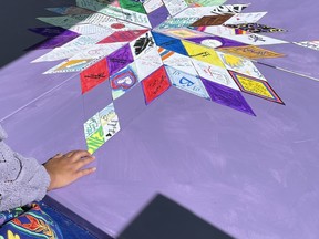 カミシャ・アレクソンさんは、2024年8月31日にサスカチュワン州サスカトゥーンで行われた薬物過剰摂取啓発デーの集会で、記念の星型ブランケットにタイルを置いている。