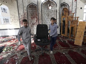 Afghan boys remove a chair from a damaged mosque in Kabul, Afghanistan, Saturday, Oct. 21, 2017, a day after a suicide attack. Suicide bombers struck two mosques in Afghanistan during Friday prayers, the Shiite mosque in Kabul and a Sunni mosque in western Ghor province at the end of a particularly deadly week for the troubled nation. (AP Photo/Rahmat Gul)