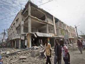Men walk near destroyed buildings as thousands of Somalis gathered to pray at the site of the country's deadliest attack and to mourn the hundreds of victims, at the site of the attack in Mogadishu, Somalia Friday, Oct. 20, 2017. More than 300 people were killed and nearly 400 wounded in Saturday's truck bombing, with scores missing. (AP Photo/Farah Abdi Warsameh)