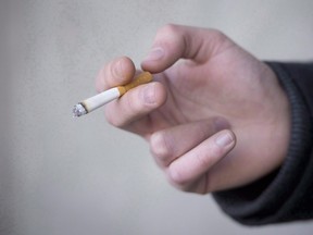 A smoker holds a cigarette during a smoke break outside a building in North Vancouver, B.C., on Jan. 20, 2014. (Jonathan Hayward/The Canadian Press/Files)