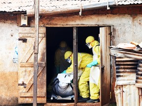 A file picture taken on October 7, 2014 shows volunteers in protective suit burrying the body of a person who died from Ebola in Waterloo, some 30 kilometers southeast of Freetown, on October 7, 2014.