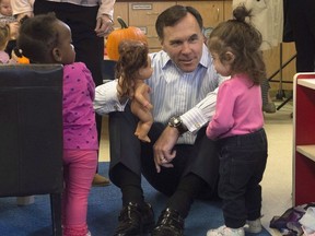 Minister of Finance Bill Morneau sits a plays with two young girls as he tours a daycare centre Wednesday October 25, 2017 in Ottawa.