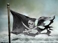 In this stock photo, a skull and crossbones flag flies with the ocean in the background.