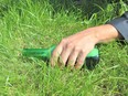 In this stock photo, a drunk man holds a beer while sleeping on a lawn.