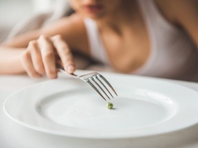 In this stock photo, a girl struggles to put a pea on a plate.