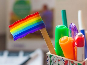 In this stock photo, a rainbow flag sits atop a popsicle stick in a container filled with school supplies.