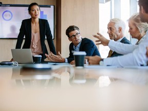 In this stock photo, a team of business people sit together in discussion around conference table.