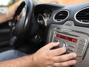 In this stock photo, a man change the volume on this car stereo.