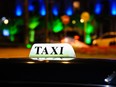 In this stock photo, a glowing taxi sign is seen on the roof of a vehicle at night.