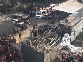 Police officers and rescuers inspect the site of an explosion at a firecracker factory in Tangerang, on the outskirt of Jakarta, Indonesia, Thursday, Oct. 26, 2017. The explosion and raging fire killed a number of people and injured dozens, police said. (AP Photo/Tatan Syuflana)