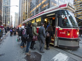 Riders board a TTC streetcar along King St. W., at University Ave.