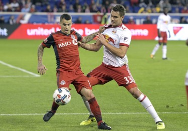 Toronto FC forward Sebastian Giovinco, left, holds off New York Red Bulls midfielder Aaron Long (33) during the second half of an MLS Eastern Conference semifinal soccer match Monday, Oct. 30, 2017, in Harrison, N.J. Toronto FC won 2-1. (AP Photo/Bill Kostroun) ORG XMIT: NJBK107 ORG XMIT: POS1710302049270976