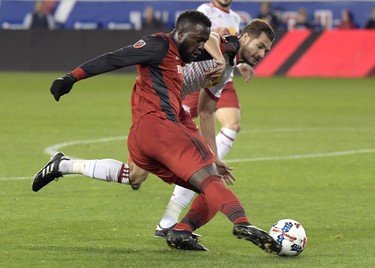 Toronto FC forward Jozy Altidore, left, passes the ball by New York Red Bulls defender Damien Perrinelle, right, during the first half of an MLS Eastern Conference semifinal soccer match Monday, Oct. 30, 2017, in Harrison, N.J. (AP Photo/Bill Kostroun) ORG XMIT: NJBK102 ORG XMIT: POS1710301939360747