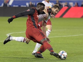 Toronto FC forward Jozy Altidore, left, passes the ball by New York Red Bulls defender Damien Perrinelle, right, during the first half of an MLS Eastern Conference semifinal soccer match Monday, Oct. 30, 2017, in Harrison, N.J. (AP Photo/Bill Kostroun)