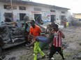 Somalis carry away a man injured after a car bomb was detonated in Mogadishu, Somalia Saturday, Oct 28, 2017.  A suicide car bomb exploded outside a popular hotel in Somalia's capital on Saturday, killing at least 10 people and wounding more than 11, while gunfire could be heard inside, police said. A second blast was heard in the area minutes later. (AP Photo/Farah Abdi Warsameh)