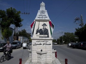 A Palestinian rides a bicycle past a monument commemorating the late Saddam Hussein in the West Bank city of Qalqiliya.